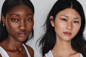 an asian model and a dark skinned model with dewy skin and white tank tops