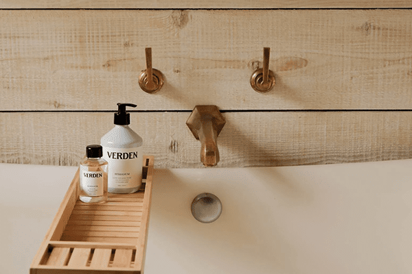 a bath tub, with VERDEN oil and body lotion bottles near the bath