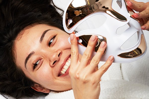 A WOMAN LAYING ON HER BACK HOLDING THE FACEWARE PRO MASK BY DR DENNIS GROSS
