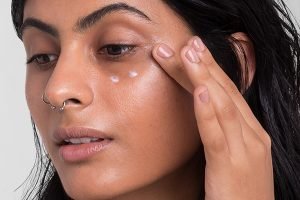 asian model applying three drops of eye cream on her eyes