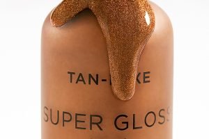 an open bottle of tan luxe gloss drops leaking out of the top all over the bottle