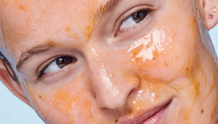 Woman wearing a orange-hued face mask and looking to the left.