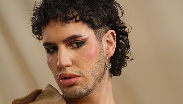 non-binary model posing with a full-face of make up