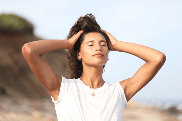 model standing in the sun with her hands in her hair