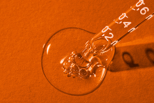 a pipette dropping a dollop of something on an orange background