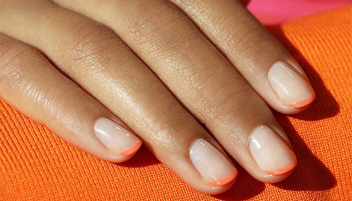 close up of models hands with an orange french tip