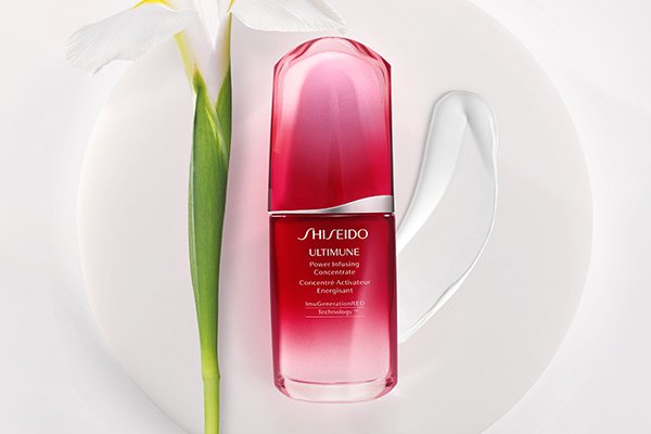 shiseido cream against a white background next to a flower stem