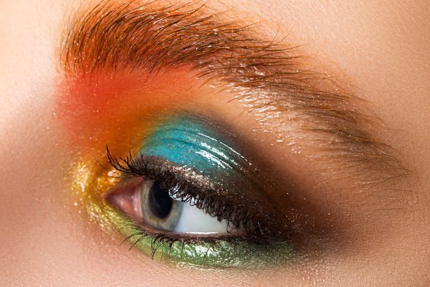  A extreme close up of a model wearing multicoloured glossy eyeshadow make up look as she’s prepping for the party season.