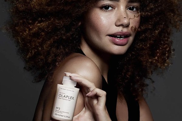 model with curly hair holding a bottle of olaplex3