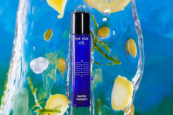 teh Nue Co.'s water therapy perfume immersed in water surrounded by lemons and leaves