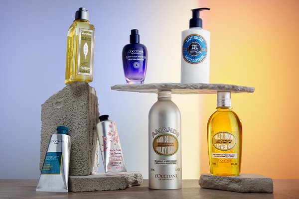 collection of L'occitane products perched on stones against a blue and orange background