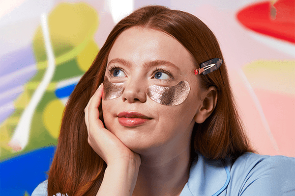 model with rose gold eye patches under her eyes looking off into the distance