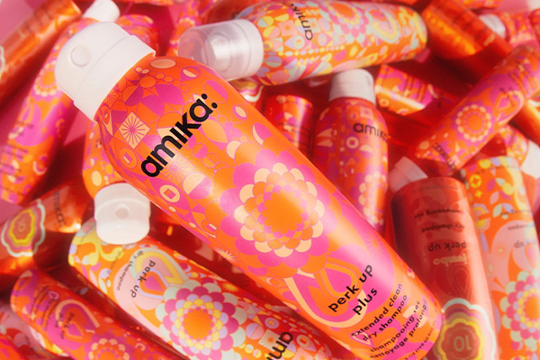 bottles and bottles of amika perk up extended platy dry shampoo all on top of eachother