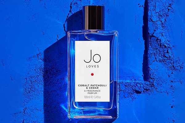 JO LOVES COBALT PERFUME AGAINST A BLUE BACKGROUND