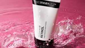 the inkey list retinol surrounded by water on a pink background