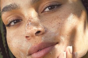 model applying a creamy product on her freckled face