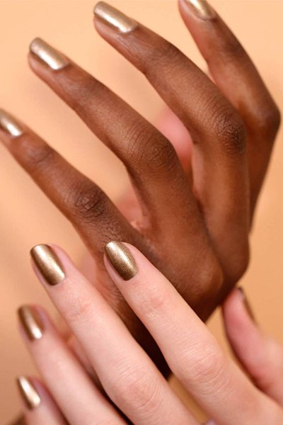 two hands, one light skinned the other dark both with gold nails