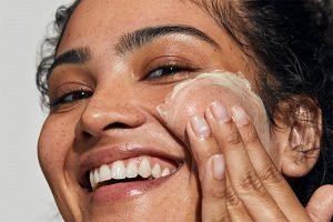 medium skinned model applying cream on her face