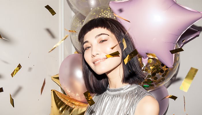 model surrounded by confetti and balloons