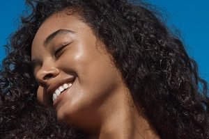 medium skinned model with super curly hair smiling