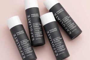 four bottles of paulas choice exfoliant bottles against a pink background