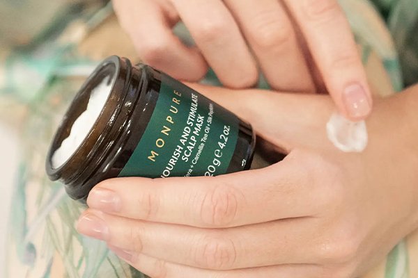 Woman rubbing dry scalp serum into her hand 