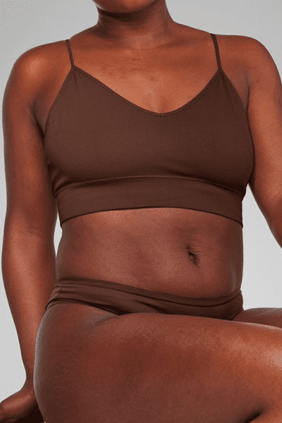 dark skinned model wearing a brown bikini sitting in a studio unretouched image