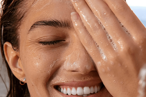 Woman hiding half her face while using a cleanser