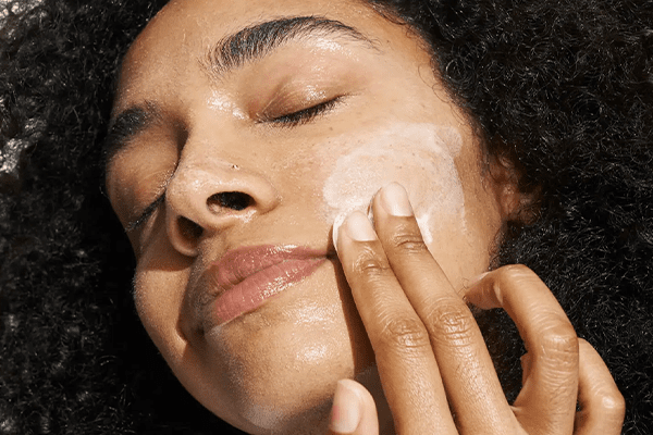 Woman applying a creamy cleanser onto her face
