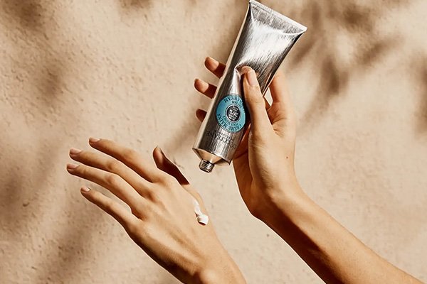 A woman putting L'OCCITANE's Shea Butter Hand Cream on her hands