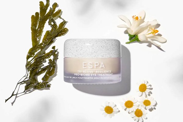 Image of ESPA tri-active resilience probiome eye cream sitting around flowers and foliage on white background.