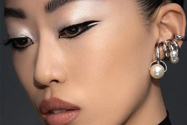 Model wears gothic style eye make up with silver earrings
