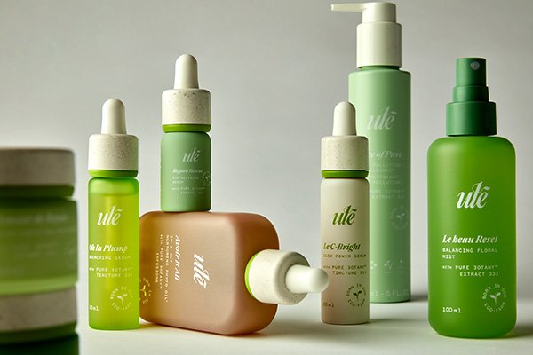 A wide shot of ule skin care products scattered around in a studio setting on a grey background