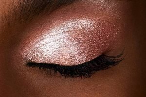 a dark skinned model with her eye closed wearing a pink scattered light eyeshadow