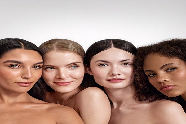A close up shot of four female models wearing tinted moisturiser on their face in a studio setting in front of a white background.