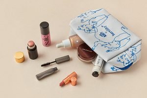 a collection of makeup sprawled out from a cult beauty x hertility bag. make up includes brands like saie, westman atelier and charlotte tilbury