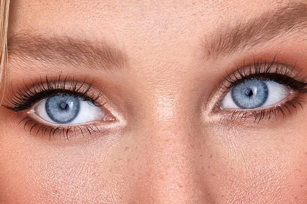 blue eyed model looking away slightly from the camera. the shot is a close up of her eyes and eyelashes. she has freckles