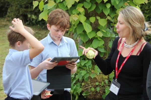 Chloe Combi, founder of The Respect Project, talking to two young schoolboys holding tablets as part of an In-School Programme workshop.