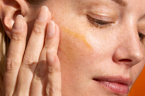 A close up of a female model using Dermalogica’s vitamin C serum to help with collagen banking, in a studio setting.