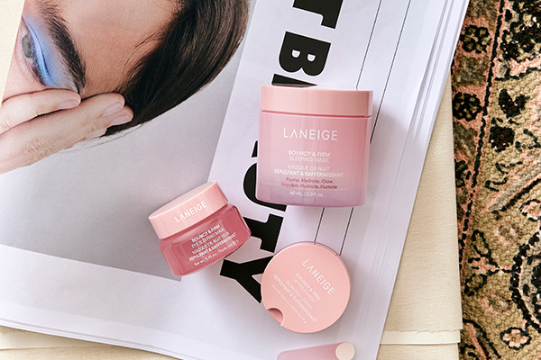 Three products from Laneige’s bounce and firm collection sitting on a Cult Beauty newspaper on top of a table top. 