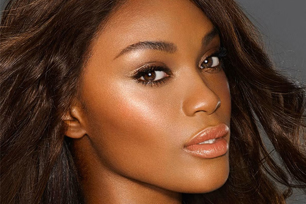 dark skinned model with cinnamon roll makeup - orangey blush, dark brown eyeshadow and cinnamon lips