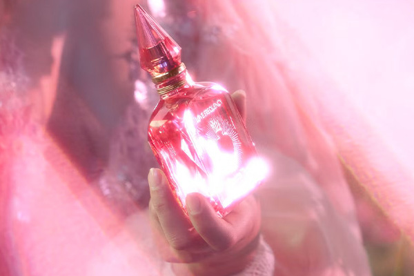 an ethereal image in shades of pink of a woman dressed in pink gossamer holding a pink bottle of charlotte tilburys love bottle.