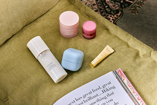 a collection of laneige products on a green sofa next to a magazine thats open to a page of writing.