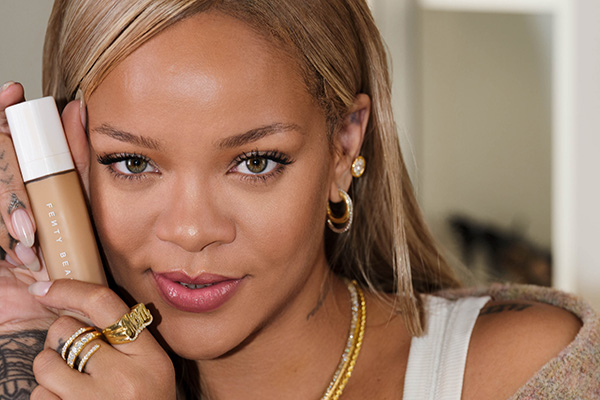 A close up image of Rihanna with blond hair holding Fenty Beauty’s Pro Filt'r Soft Matte Longwear Foundation to her face.