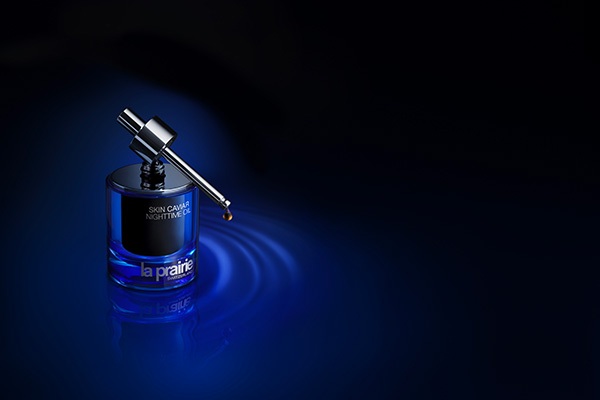 A product image of La Prairie’s Skin Caviar night oil sat on a deep blue background in a studio setting.