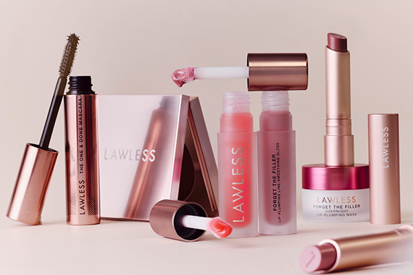 a collection of lawless beauty products shot in a studio against a neutral background. some of the lipglosses have the doe-foot placed ontop of open glosses, some of the lipsticks are open