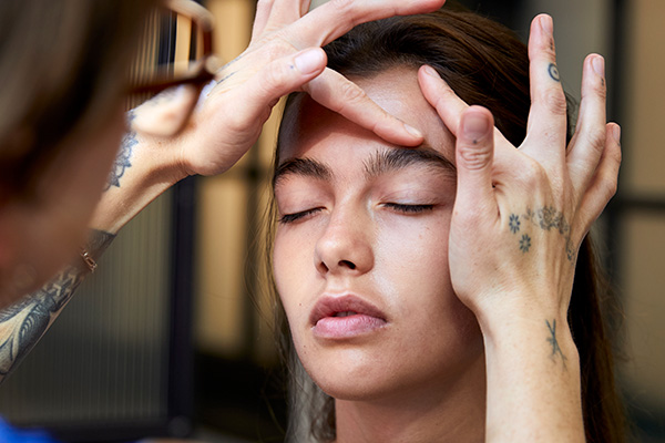 A close up image of a female model getting a face massage. backstage on set. 