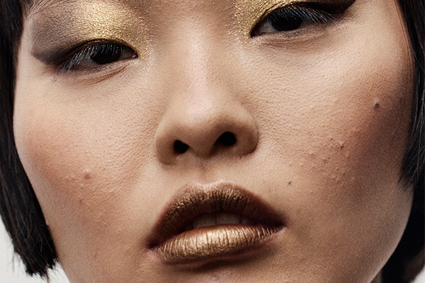 asian model with a short bob with gold eyeshadow and gold lips