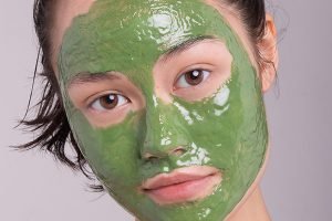 model with a green face mask on her face