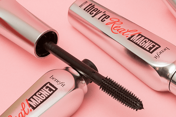 Two of Benefit's They're Real mascara in a studio setting on a pink background